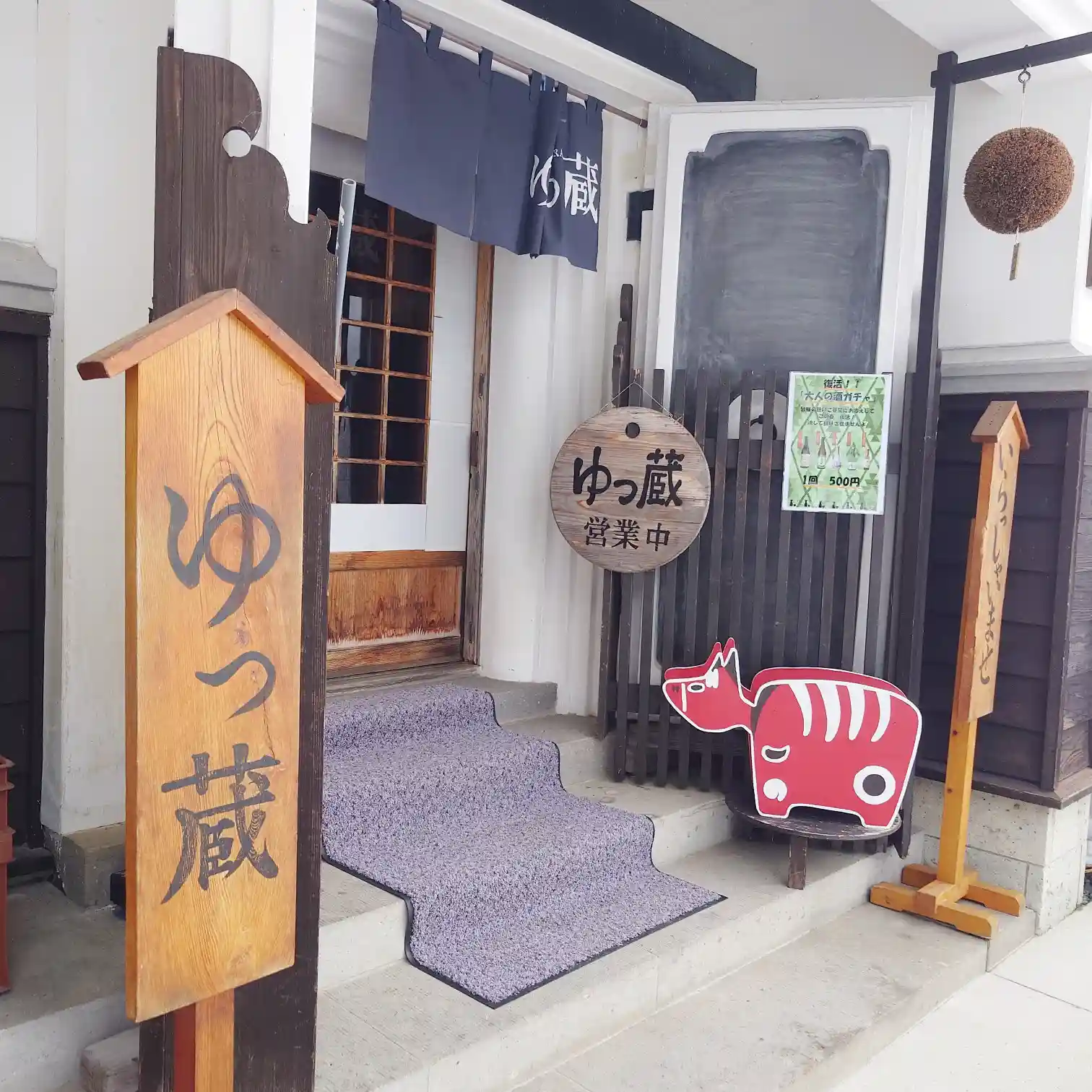 榮川酒造 ゆっ蔵の入口ディテール｜のれんと杉玉、赤べこが迎えるエントランス