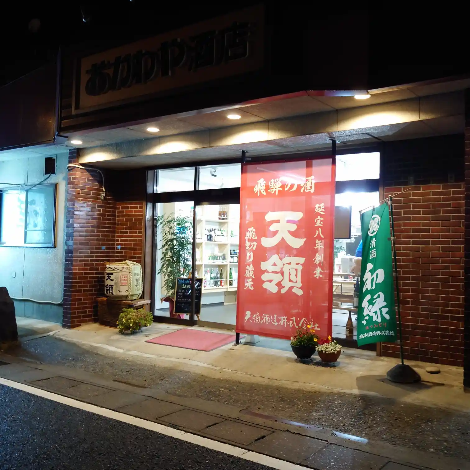下呂温泉街にある「おがわや酒店」の外観。赤い看板と日本酒の暖簾が目印の老舗酒屋。
