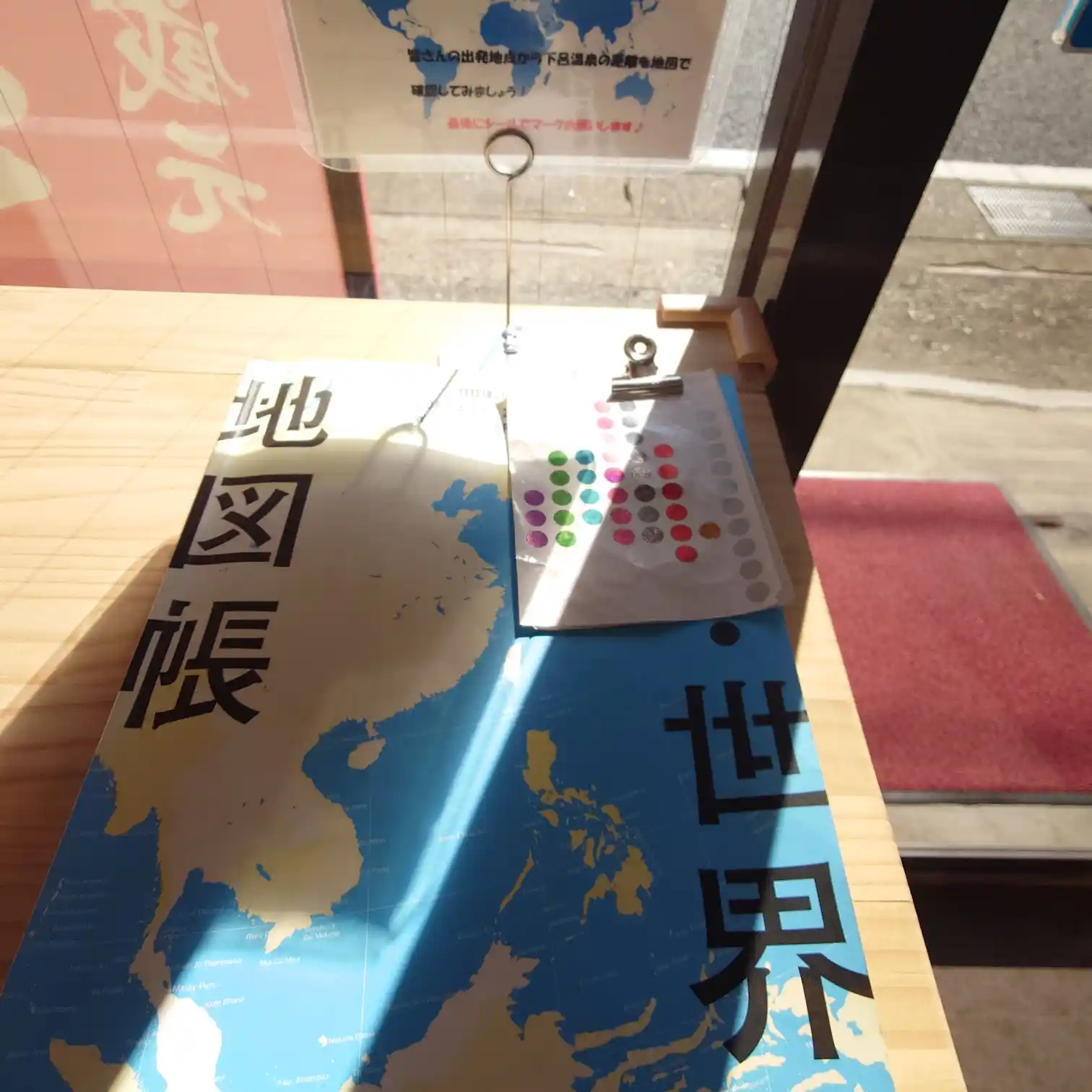 世界地図帳とシール。訪問者が自分の出発地をマーキングできる。