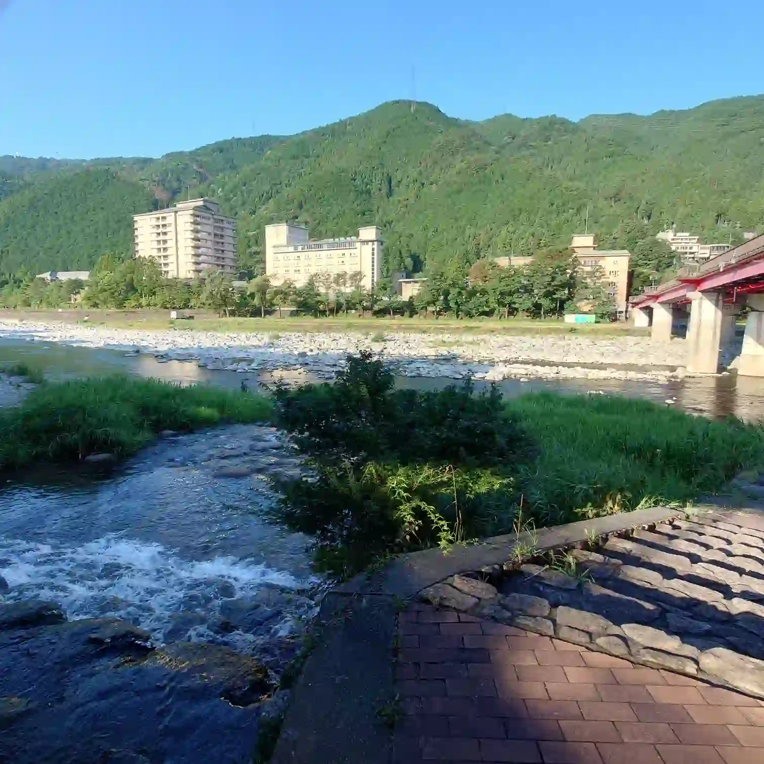 阿多野川が飛騨川に合流する地点、赤い橋と対岸の温泉ホテル群を望む。ここから菊半旅館へ戻る復路の合流ポイント—下呂温泉・菊半旅館発3kmコース