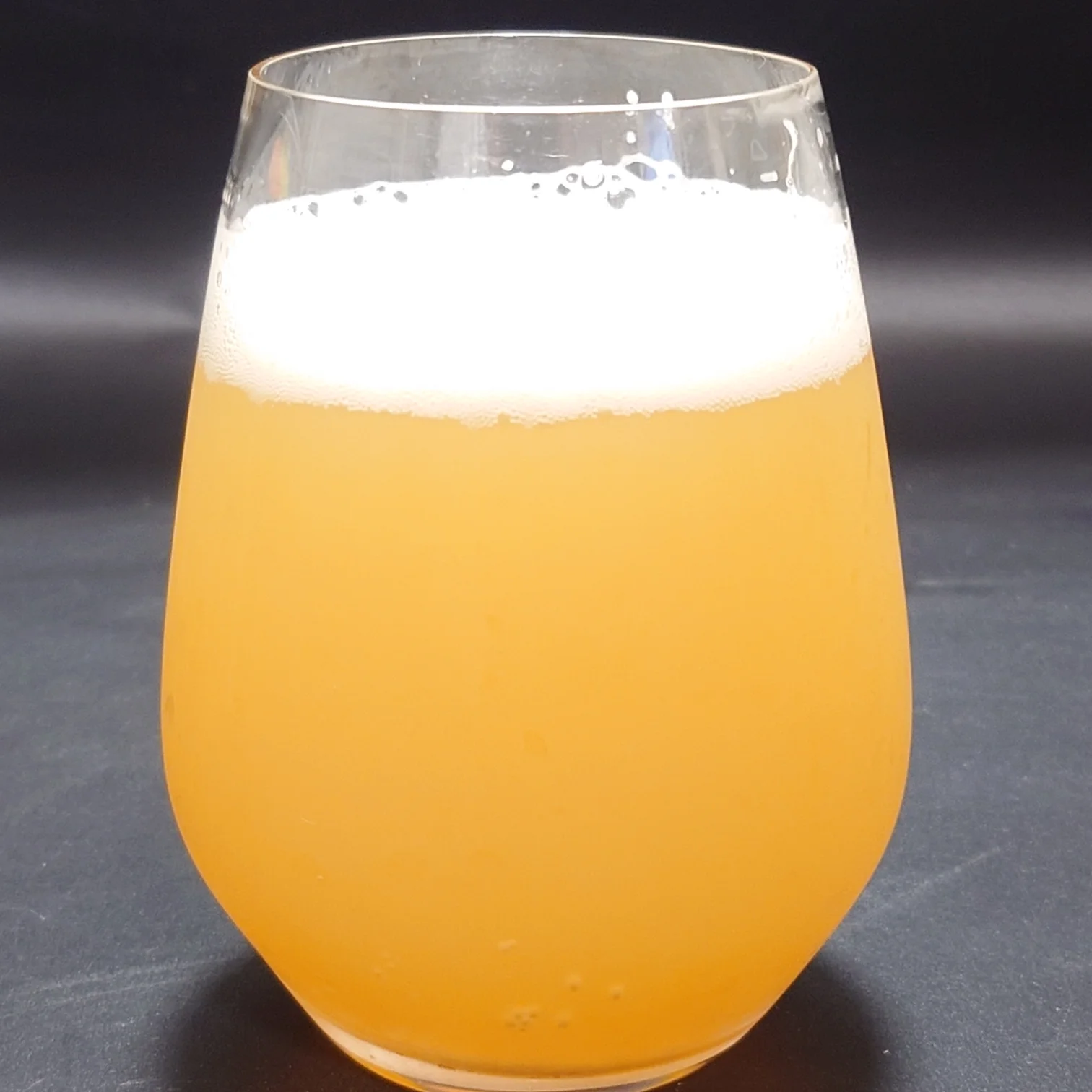 ヤッホーブルーイング『有頂天エイリアンズ HAZY IPA』をグラスに注いだ様子。濁りのあるオレンジ色の液色に、きめ細かな白い泡がトップに広がっている。