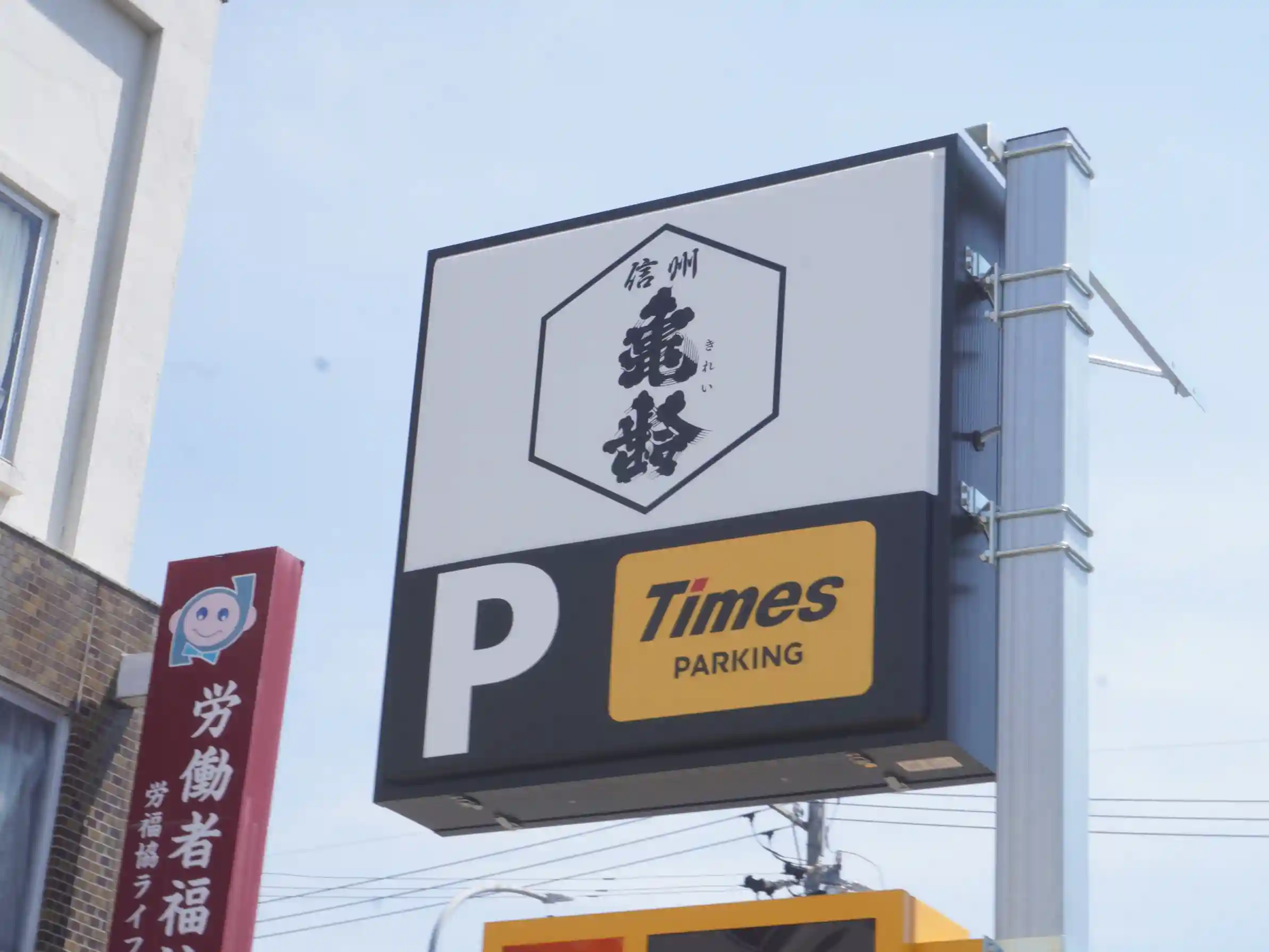 「信州亀齢」のロゴ入り看板とTimesのPサイン。岡崎酒造へ向かう際の駐車の目印（勤労者福祉センター近く）