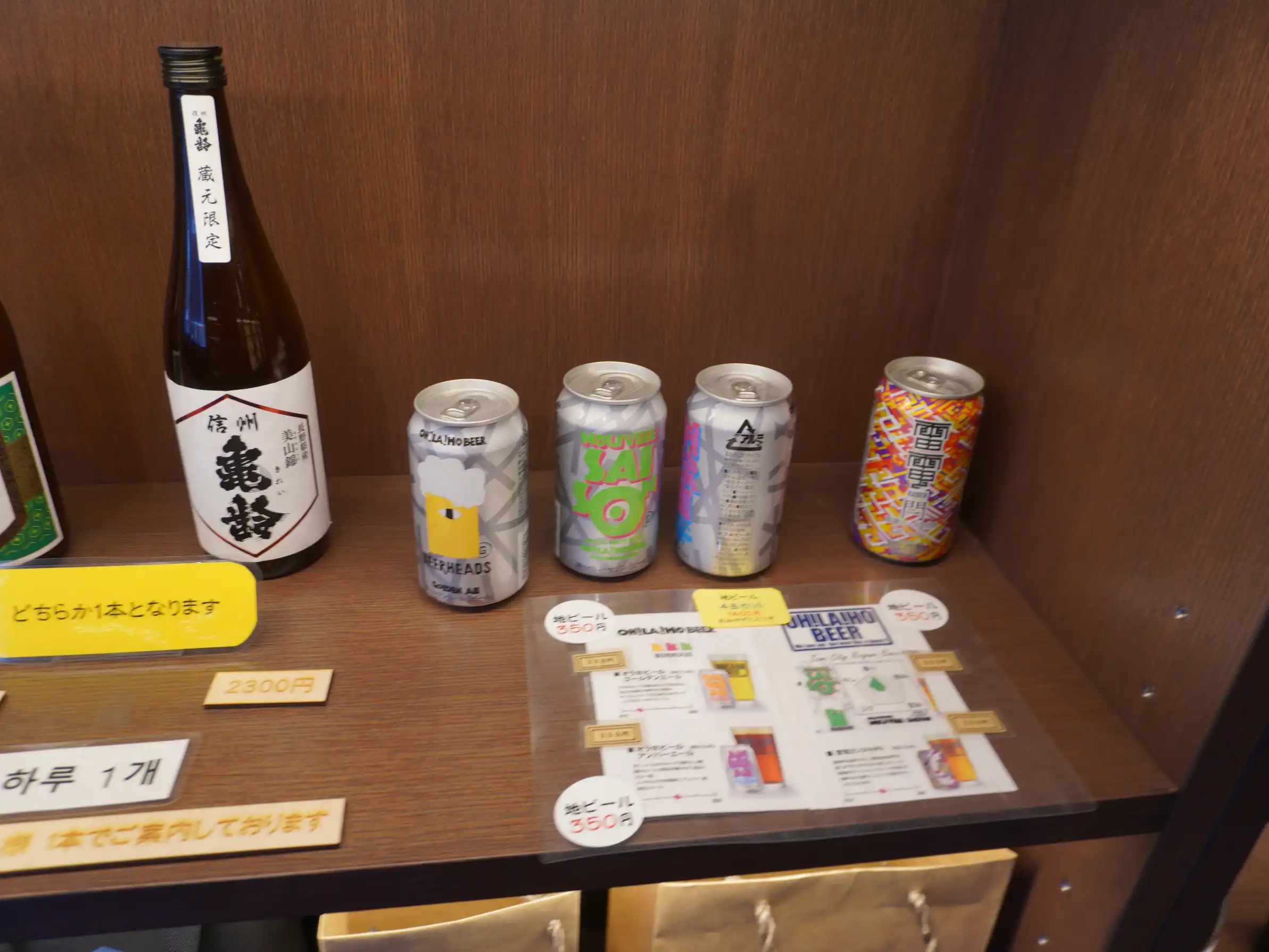 信州亀齢（蔵元限定）の瓶とオラホビールが並ぶ店頭棚。銘柄と本数は日によって変動