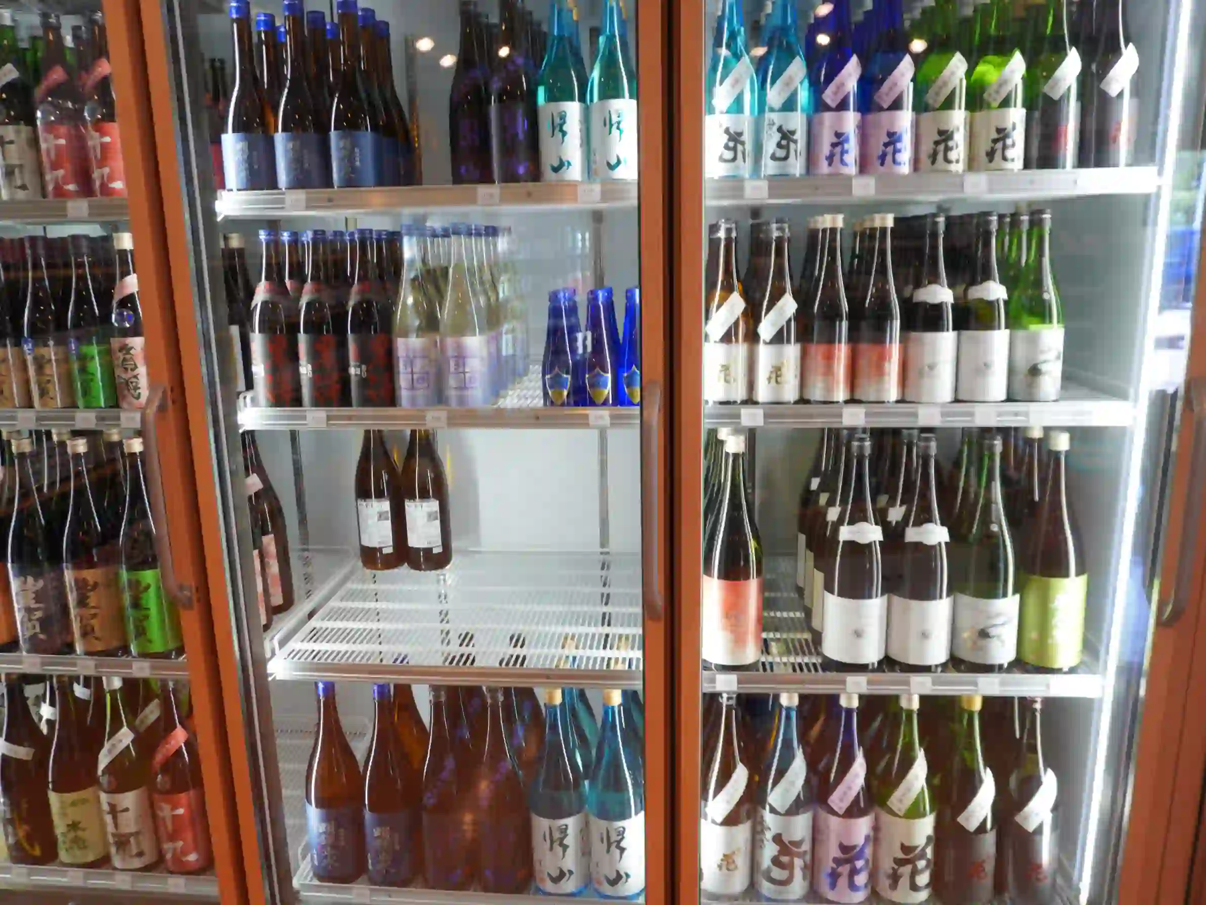 青・緑・茶の瓶が並び、首掛け札が付いた日本酒が整列。