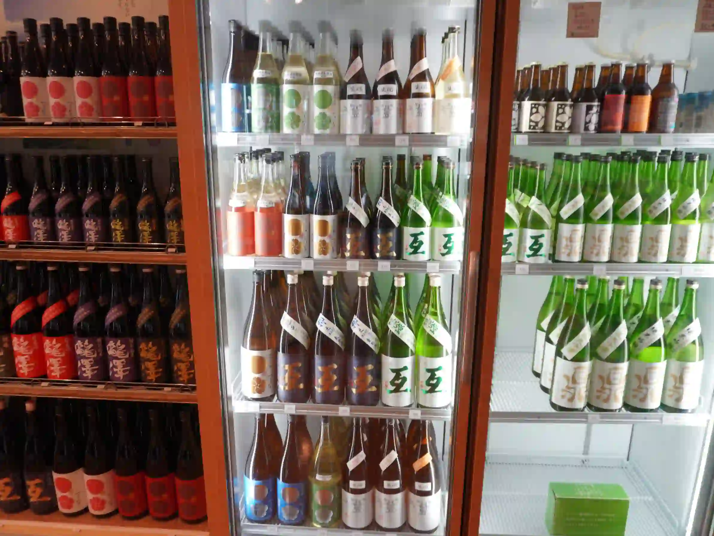 左に赤・紫ラベルの常温棚、中央と右に日本酒の冷蔵ショーケース。