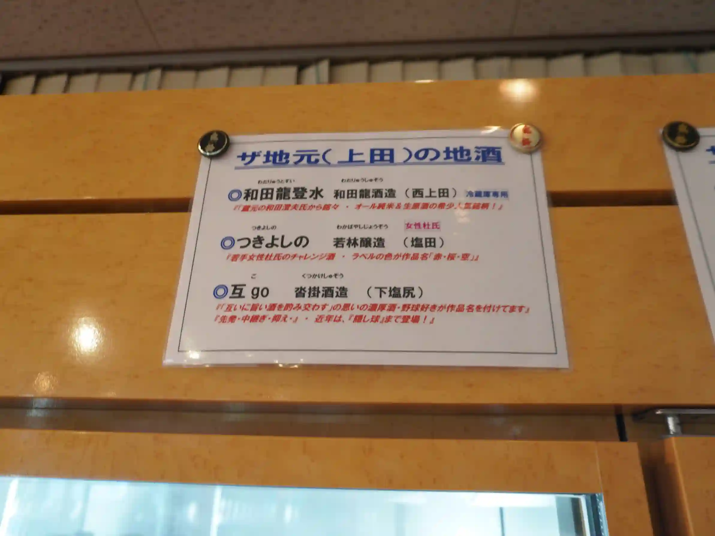 店内掲示「ザ地元(上田)の地酒」。和田龍登水・つきよしの・互goなどの案内。