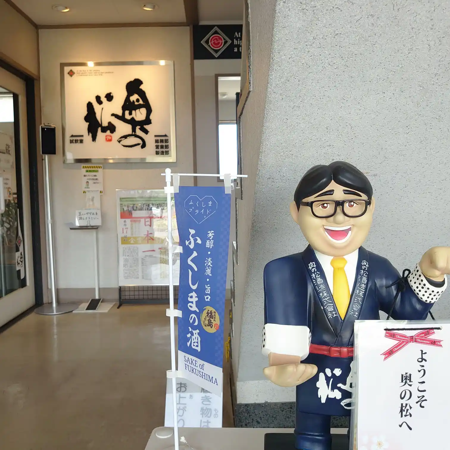 奥の松酒造の入口ロビーとウェルカムマスコット、のぼり旗が並ぶ様子