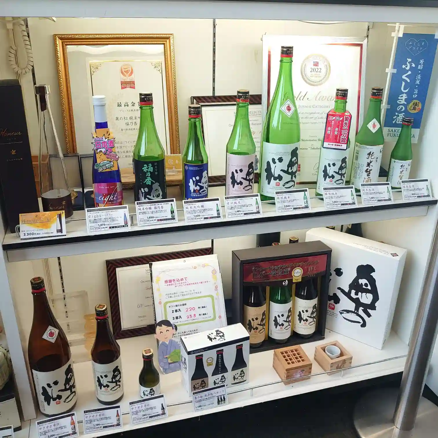 奥の松酒造の受賞パネルと日本酒ラインアップが並ぶ陳列棚