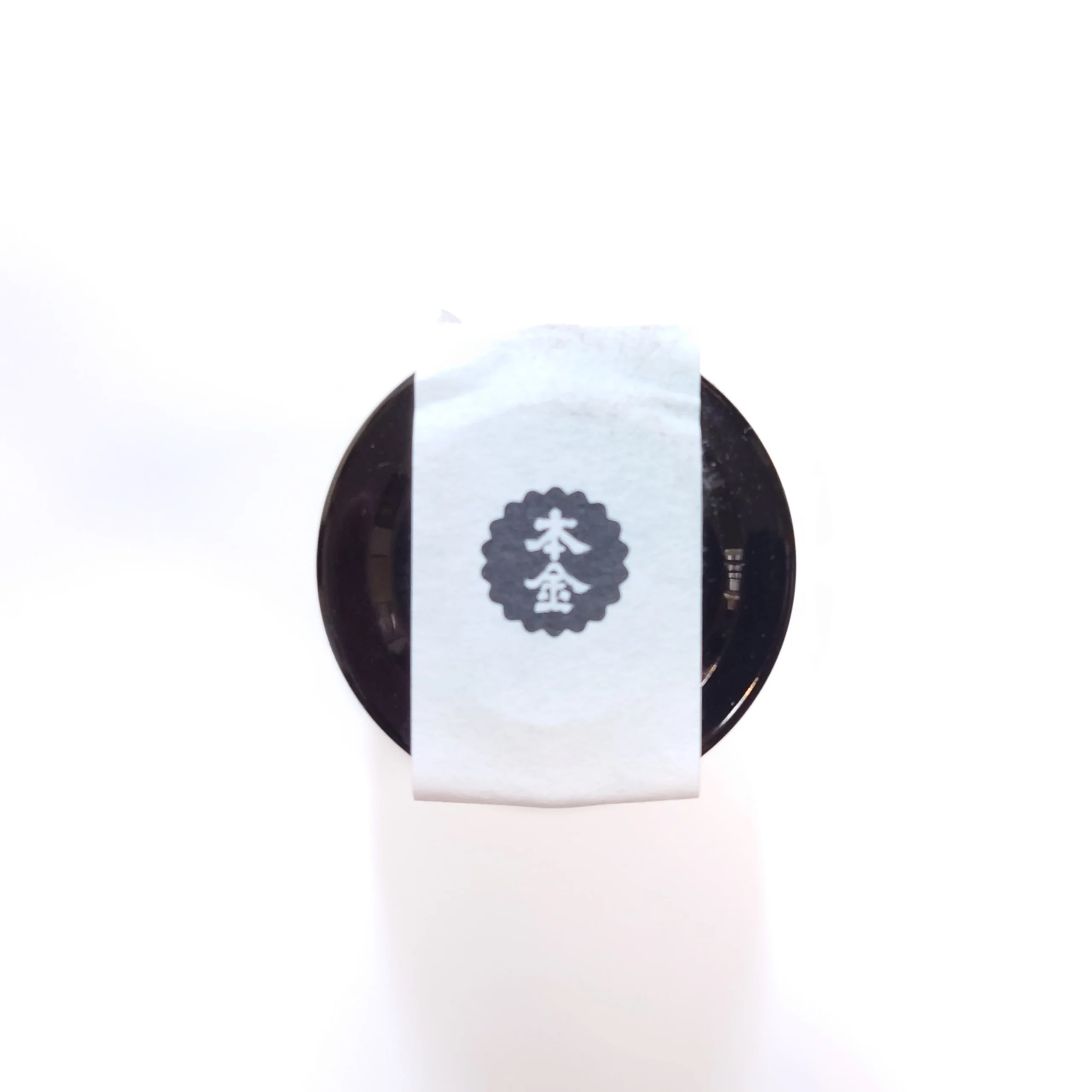 長野・諏訪の日本酒「野良 Nora」—瓶口の天面から見た黒栓に本金ロゴの封紙を貼ったクローズアップ