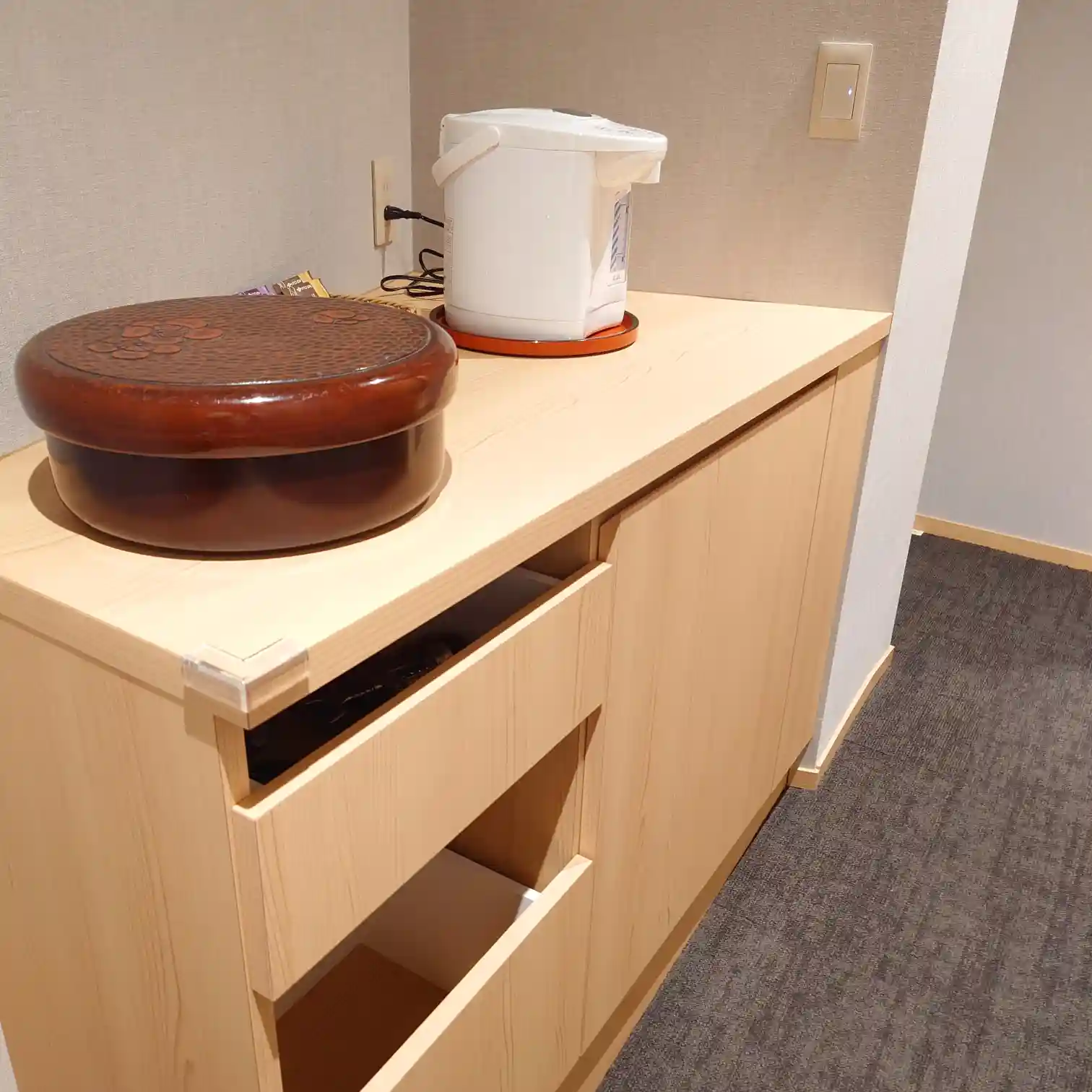 玄関横の収納カウンター。湯沸かしポットと茶器の入った丸い容器を設置。