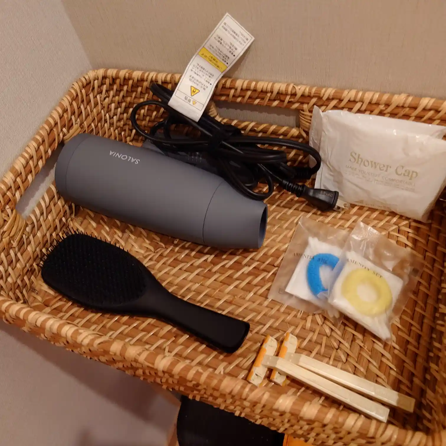 アメニティのカゴ。ドライヤー（SALONIA）、ヘアブラシ、シャワーキャップ、ヘアゴム、歯ブラシなど。