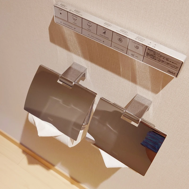 INAX製ウォシュレット操作パネルと2連のステンレス製トイレットペーパーホルダー。