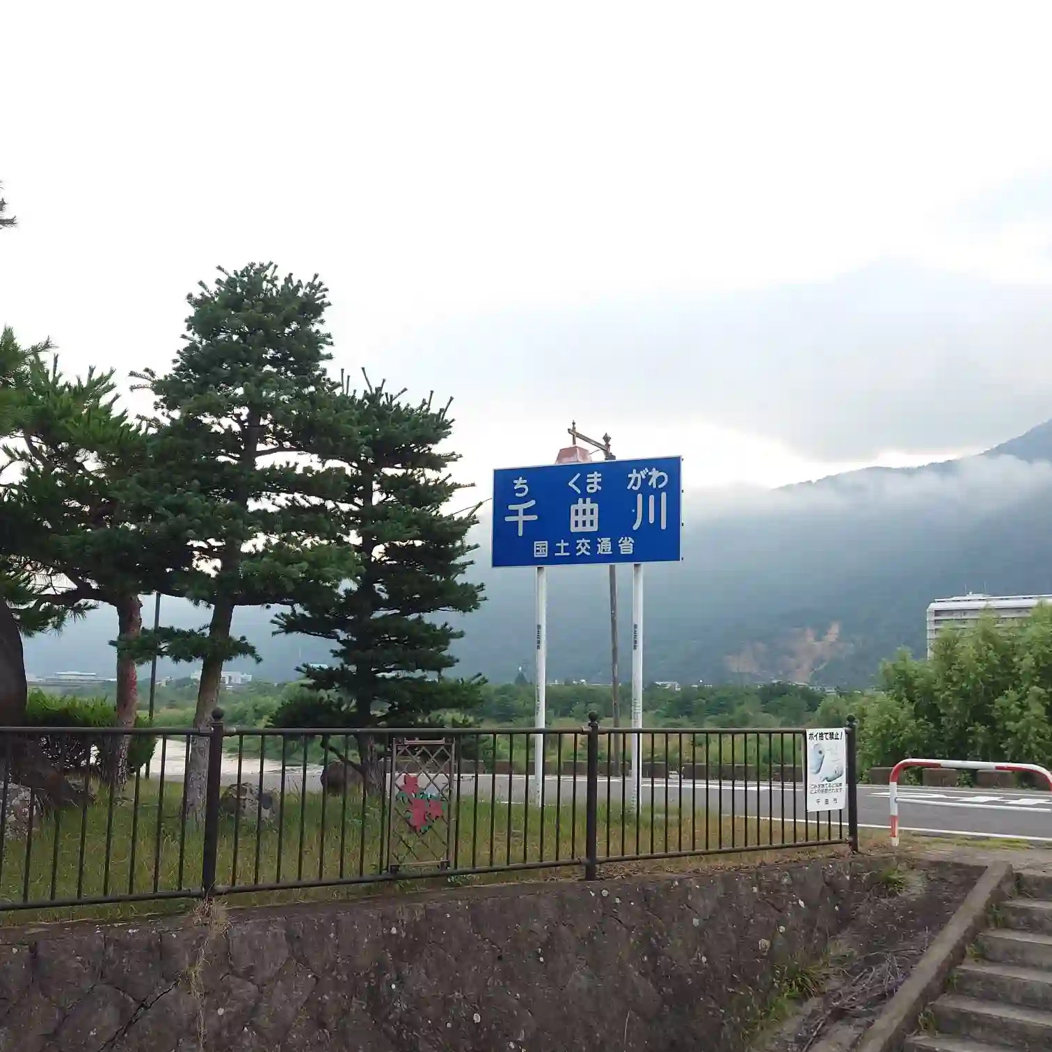 千曲川の青い案内標識と朝霧に包まれた戸倉上山田温泉の山並み