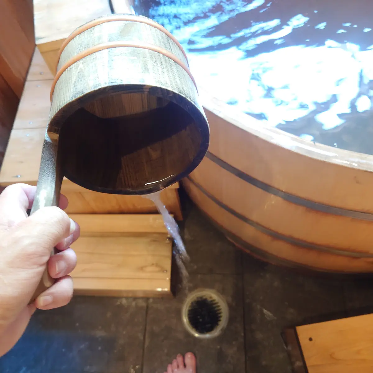 木桶の柄杓から注がれる湯と客室露天風呂の丸い湯船
