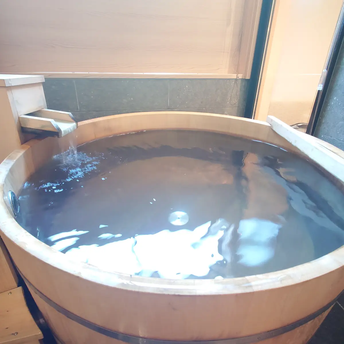 木桶の丸い湯船に満たされた戸倉上山田温泉の客室温泉と静かな湯面