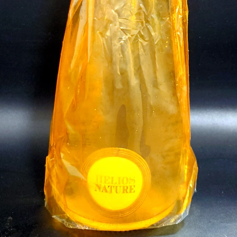 スパークリングワイン「HELIOS NATURE」ボトル下部とラベル部分をクローズアップ(オレンジフィルム包装)