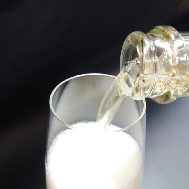 HELIOS NATURE スパークリングワイン 泡立つ注ぎ入れシーン スパークリングワイン「HELIOS NATURE」をグラスに注ぎ、細かな泡が一面に広がる様子