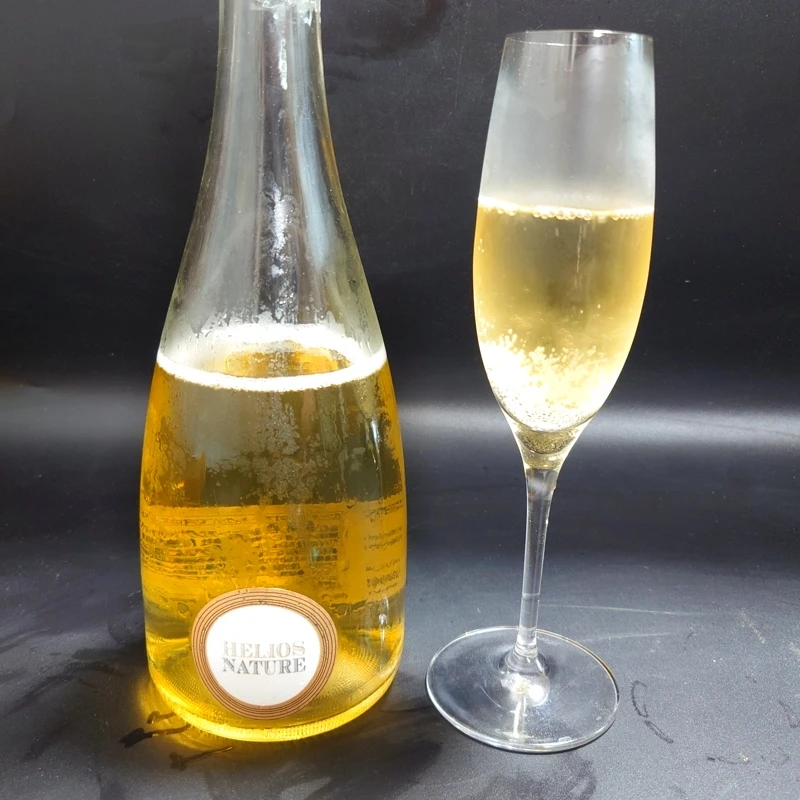 HELIOS NATURE スパークリングワイン ボトルとグラスショット スパークリングワイン「HELIOS NATURE」のボトルと注がれたフルートグラス