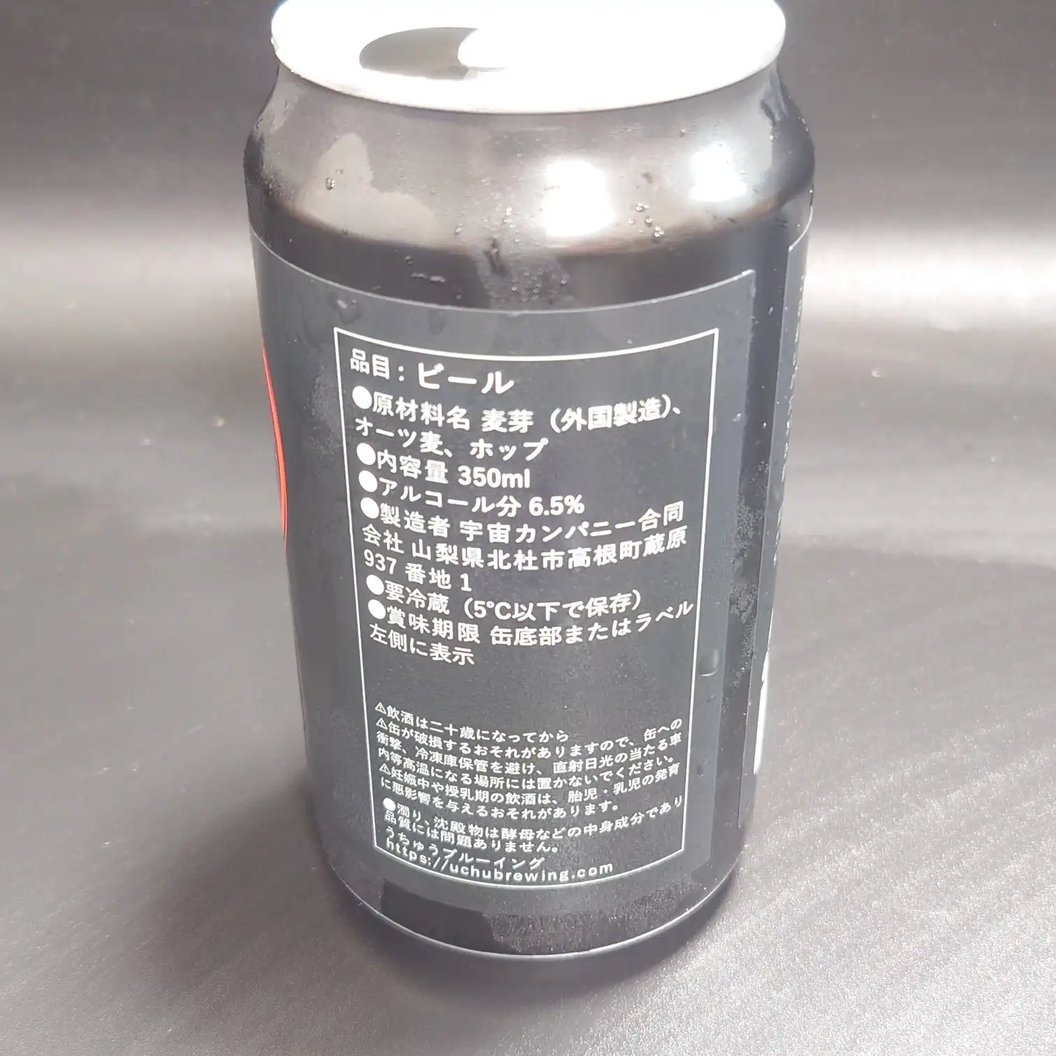 UCHU BREWING 宇宙ビール 裏ラベル 山梨・北杜のクラフトビール 350ml缶 アルコール6.5% 要冷蔵表示 山梨県北杜市 宇宙カンパニー合同会社 UCHU BREWING の350mlビール缶裏ラベル 原材料表示とアルコール分6.5% 要冷蔵5℃以下の注意書きが読み取れる 黒地デザインに白文字