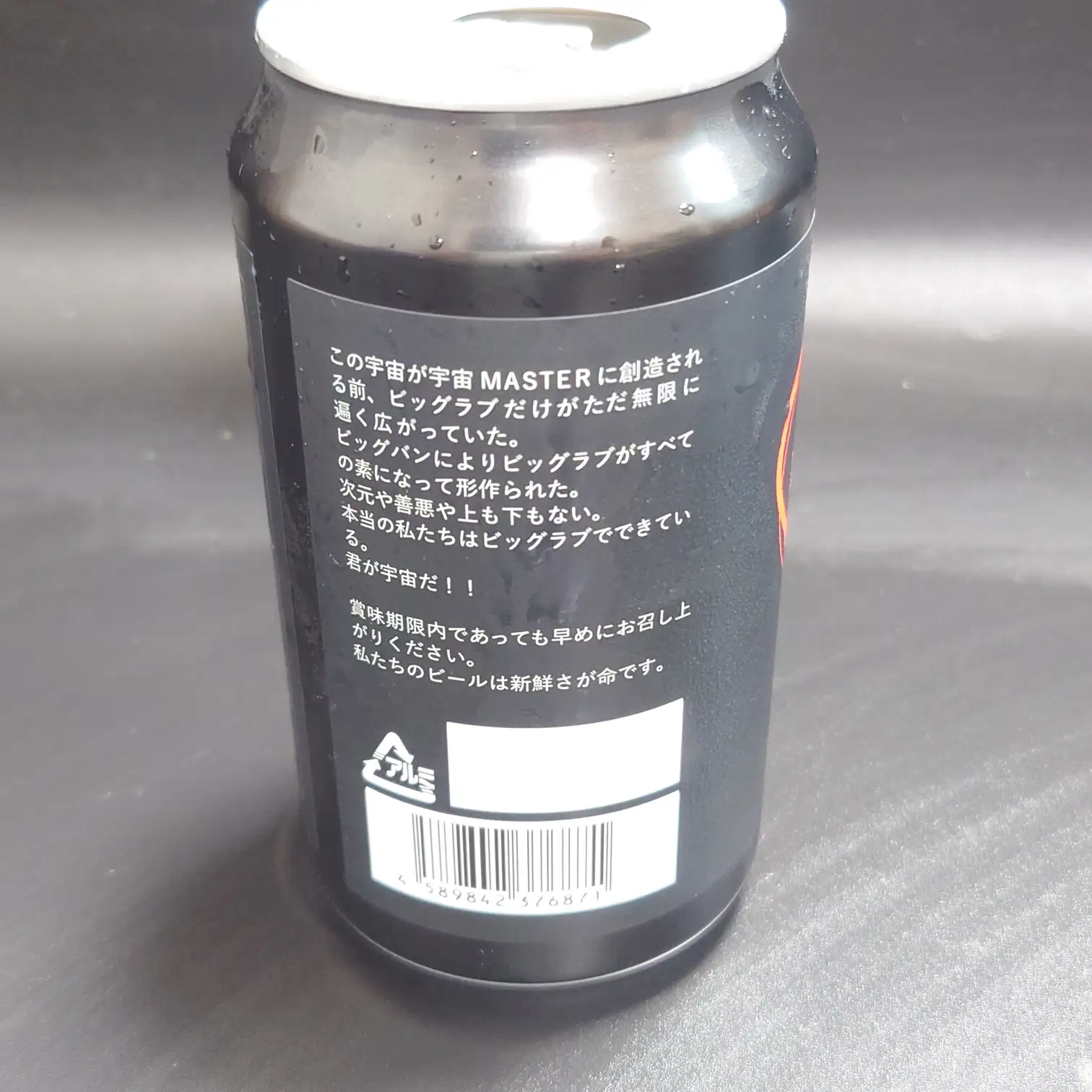 宇宙ビール 側面ラベル ストーリーテキスト入り 黒地デザインとバーコードが見える UCHU BREWING 宇宙ビール 黒い350ml缶の側面 ストーリー文とバーコード アルミ缶マーク 水滴がついた質感がわかる