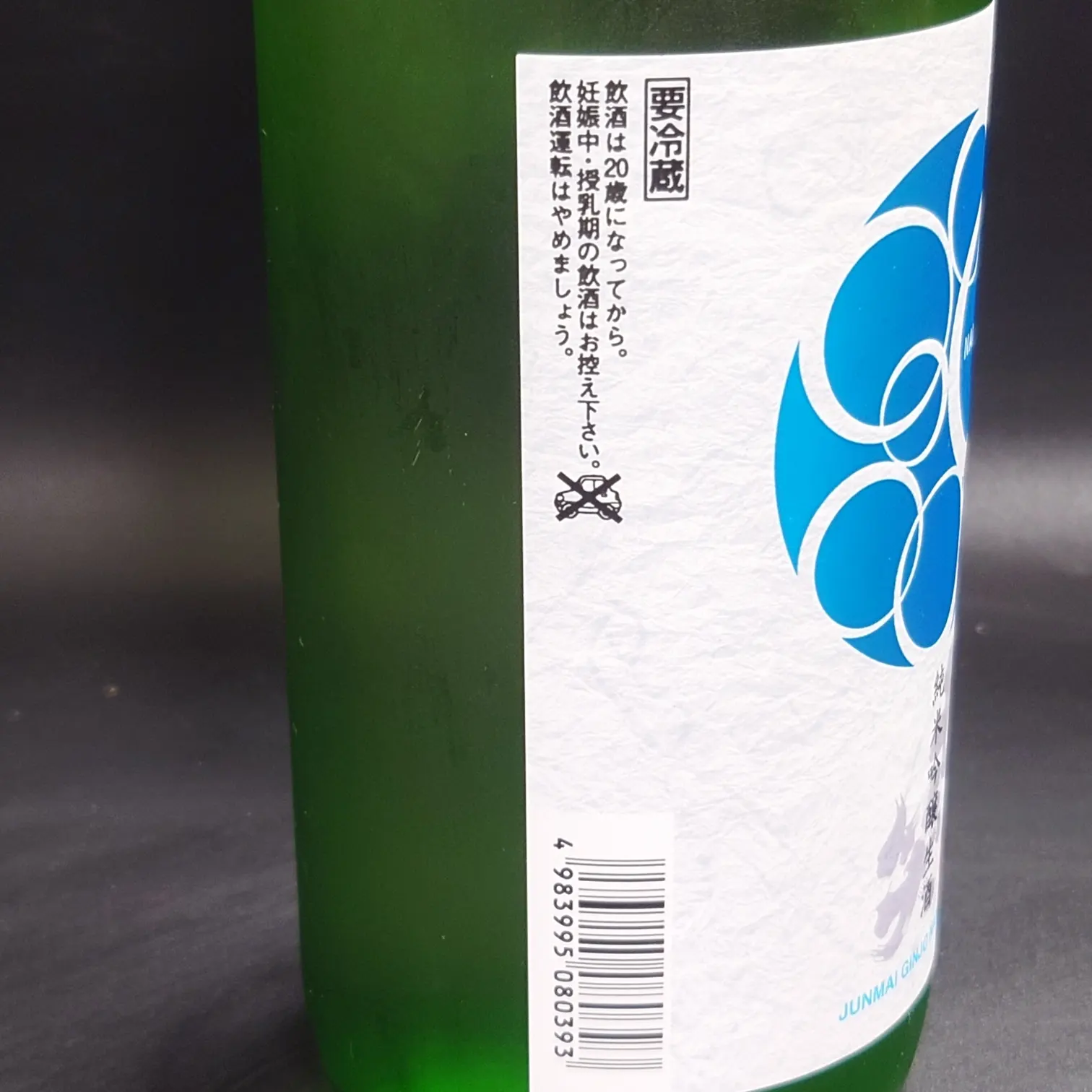 七笑 純米吟醸生酒の裏ラベル 注意書き 要冷蔵表記 バーコードを含む情報面 黒背景で紙ラベルの質感が見える