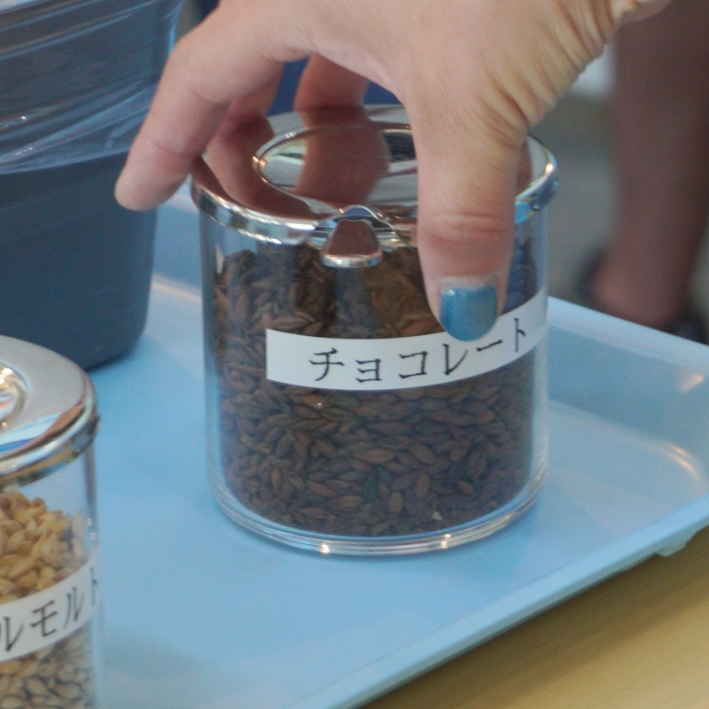 チョコレートモルトを手に取り香り確認|よなよなエール 大人の醸造所見学 長野・佐久|ヤッホーブルーイング よなよなエール 大人の醸造所見学|チョコレートモルトの瓶を手に取り香りを確かめる原料体験