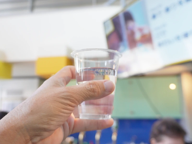 長野・佐久|テイスティングの合間の和らぎ水—ヤッホーブルーイング試飲室 和らぎ水のカップを手に掲げる