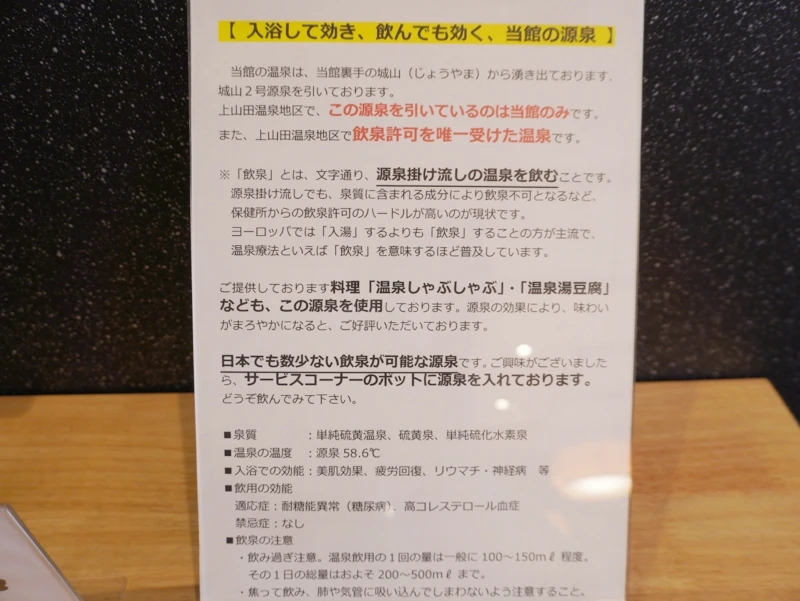 ホテル晴山の飲泉案内パネル。城山2号源泉の説明、飲用の目安、館内料理での活用が記載。