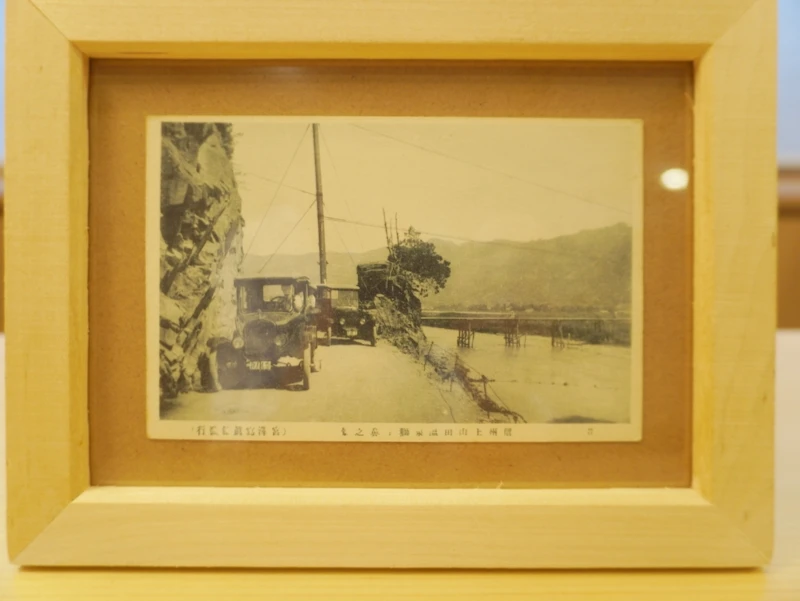 ホテル晴山 所蔵の古写真|千曲川沿いの崖道を走るフォードT型(戸倉) 戸倉上山田温泉・ホテル晴山の所蔵古写真|千曲川沿いの崖道を走るフォードT型と木製やぐらの見える風景(額装)