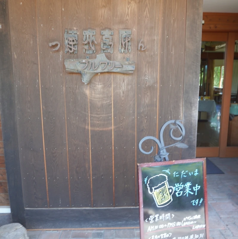 嬬恋高原ブルワリーの入口と営業中ボード 入口と黒板、店内の様子が見える