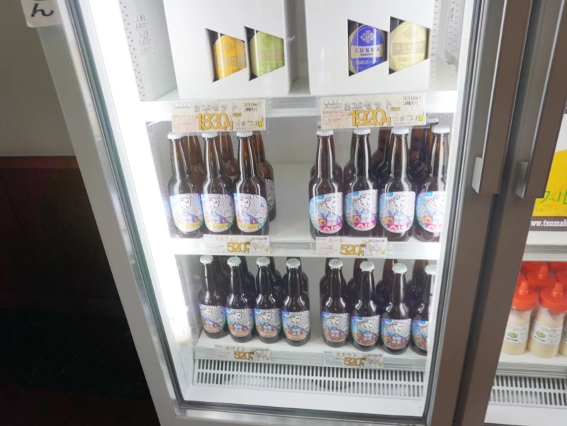 冷蔵ケースに並ぶ瓶ビール(嬬恋高原ブルワリー) 群馬・嬬恋高原ブルワリーの店内冷蔵ケース、330ml瓶ビールがラベル違いで並び価格表示が付いている様子