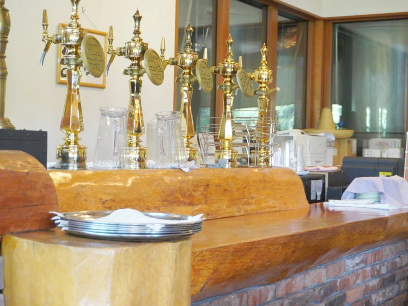 木カウンターに並ぶ真鍮タップ(嬬恋高原ブルワリー) 木とレンガのカウンターに並ぶ真鍮タップ