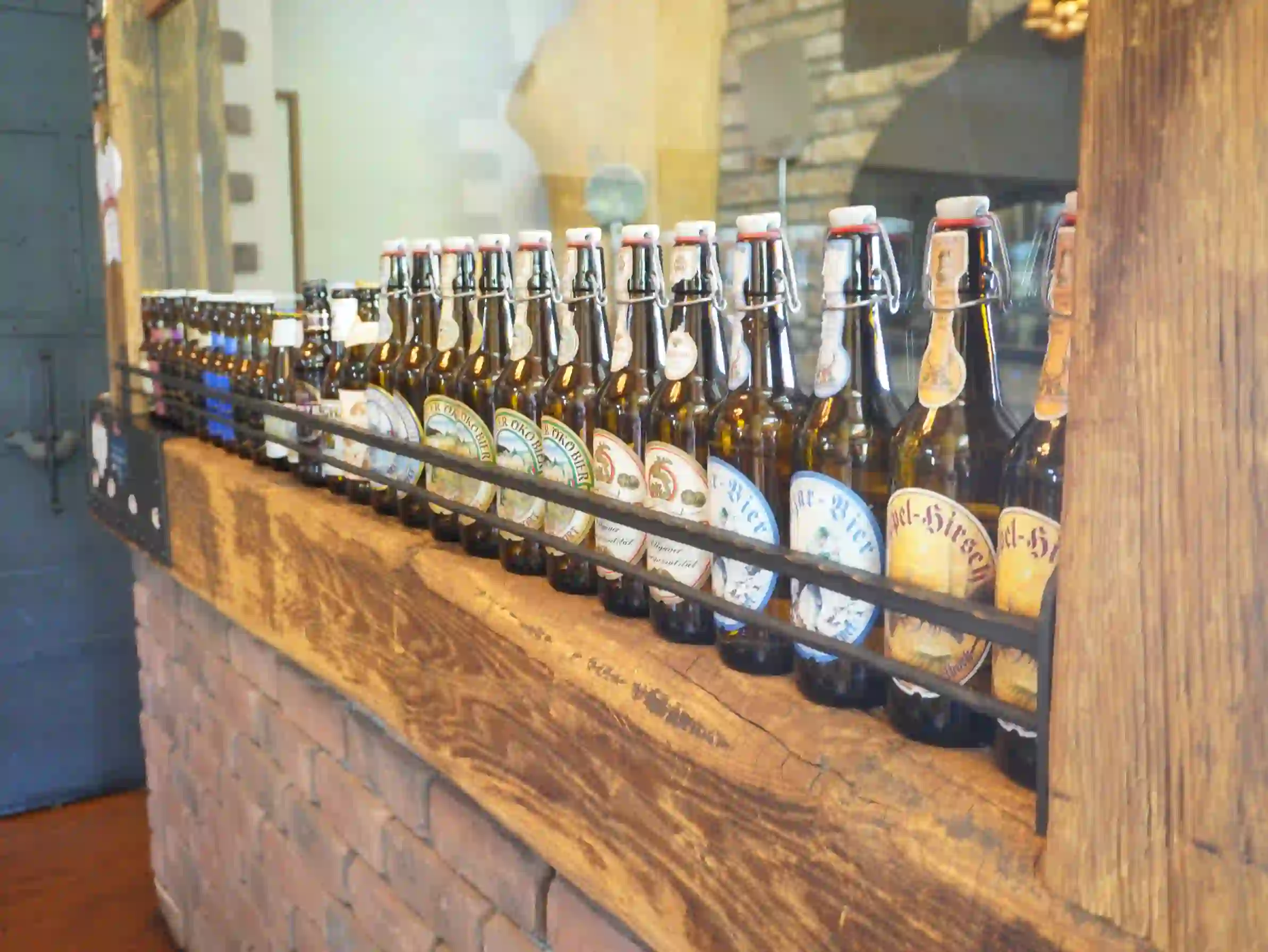 整列したディスプレイ用ビール瓶(嬬恋高原ブルワリー) 木製カウンターに整列した栓付きビール瓶のディスプレイ
