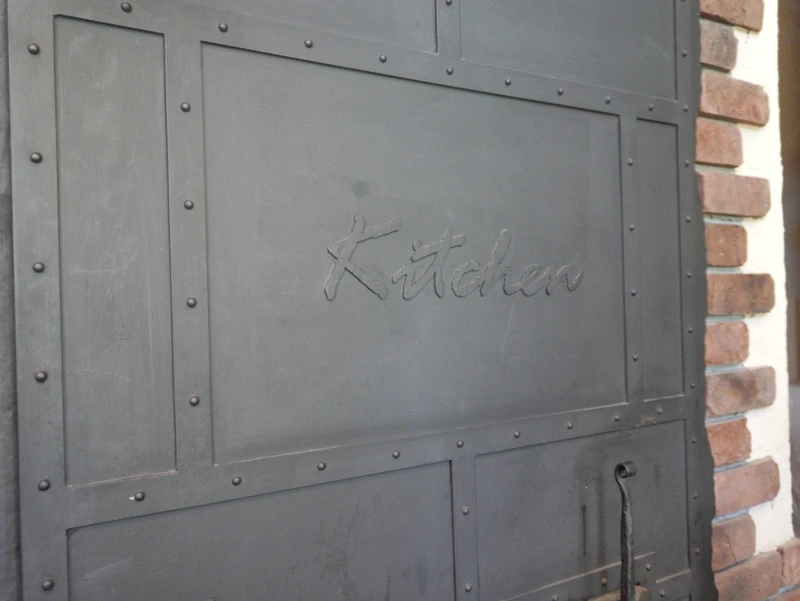 嬬恋高原ブルワリーの“Kitchen”鋼板パネル 黒い鋼板パネルの“Kitchen”刻印とリベット