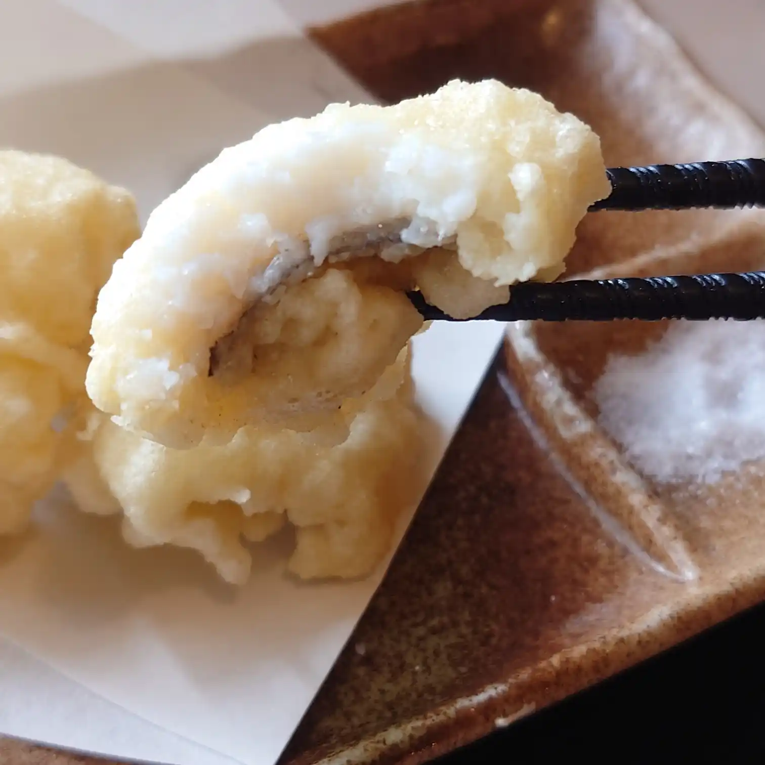 如月|鱧天ぷらのアップ 如月の鱧(はも)天ぷらを箸で持ち上げた瞬間。ふんわり衣の中に淡白で上品な身がのぞく