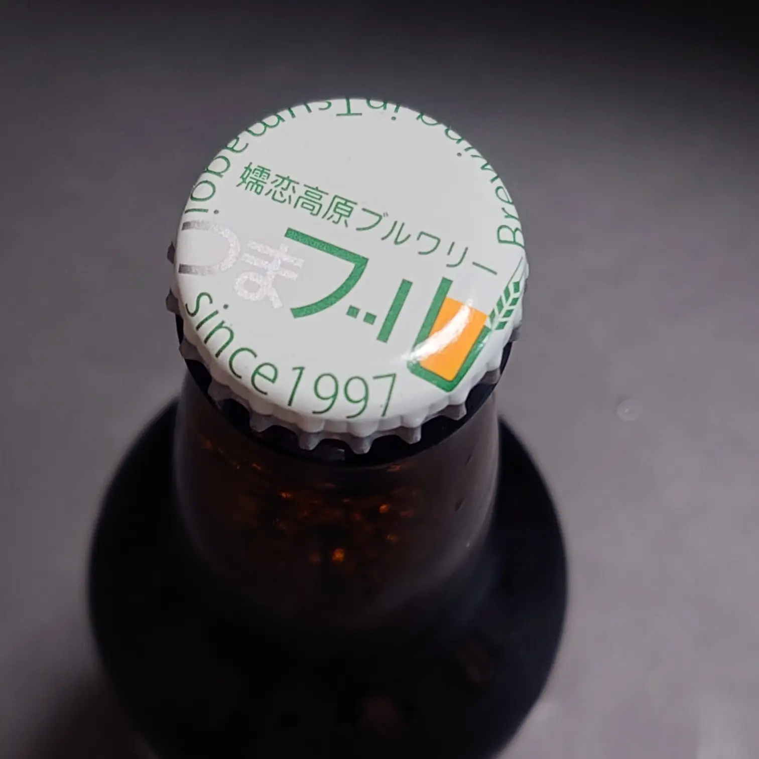 つまブル 高崎ポーター|王冠キャップのロゴ(since 1997) つまブル 高崎ポーターの王冠キャップを真上から 白地に緑ロゴつまブル 嬬恋高原ブルワリー since 1997 表記 自宅撮影のマクロ