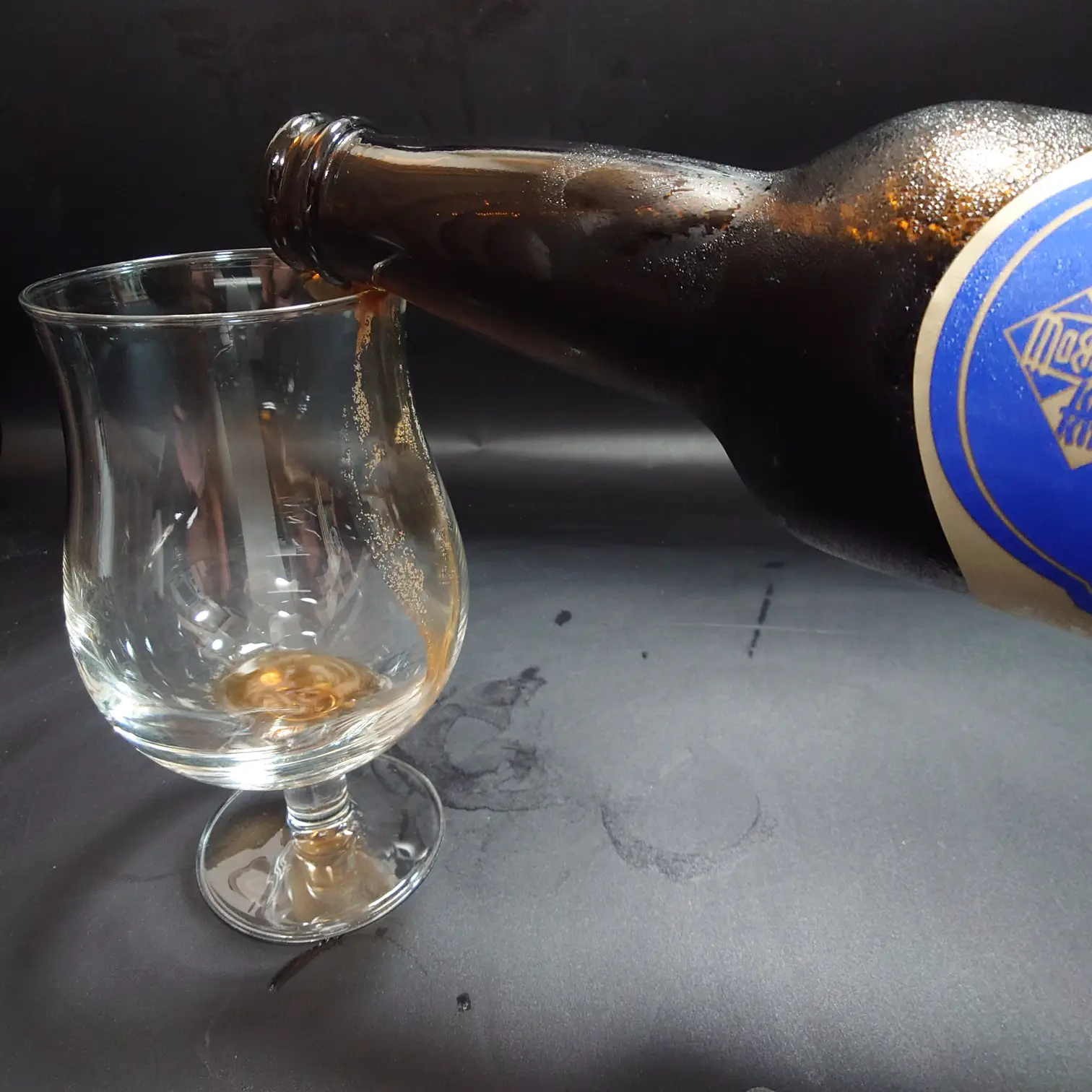 つまブル 高崎ポーター|注ぎ始めのシーン(チューリップグラス) つまブル 高崎ポーターをチューリップグラスに注ぎ始める瞬間 青ラベルのボトルから最初の一滴 黒背景で結露した瓶 自宅撮影