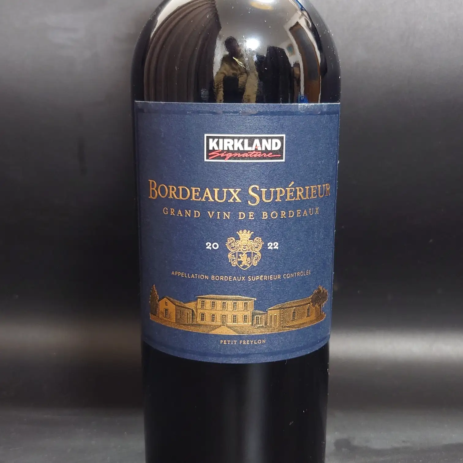 カークランド ボルドー・シュペリュール 2022 ボトル正面ラベル コストコ限定カークランドシグネチャーの赤ワイン、ボルドー・シュペリュール2022のボトル正面ラベルを撮影した写真。深い青のラベルに金色の建物と紋章が印象的。