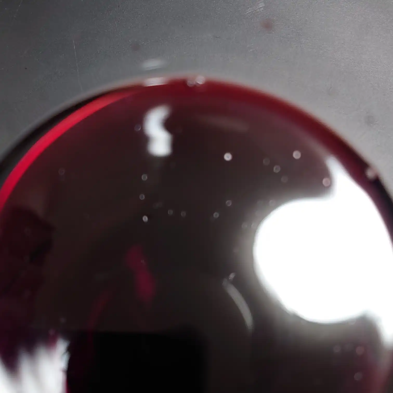 カークランド ボルドー・シュペリュール 2022 液面のルビー色 カークランド ボルドー・シュペリュール2022の液面を真上から撮影。深いルビーレッドに紫の縁が浮かび、照明の反射が美しく映える。