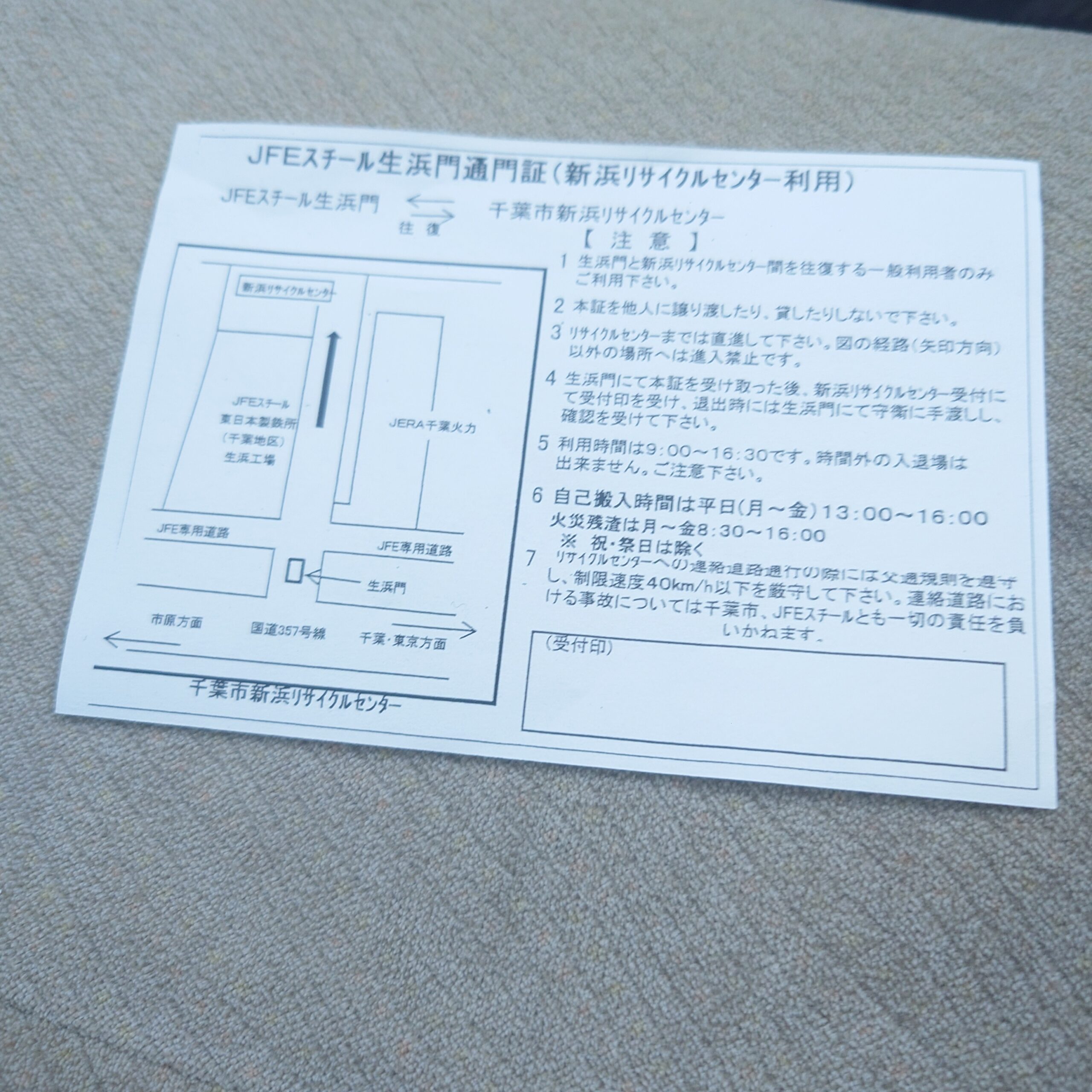 新浜リサイクルセンター利用時に必要なJFEスチール生浜門通用証の案内用紙を、屋内で広げて確認している様子。