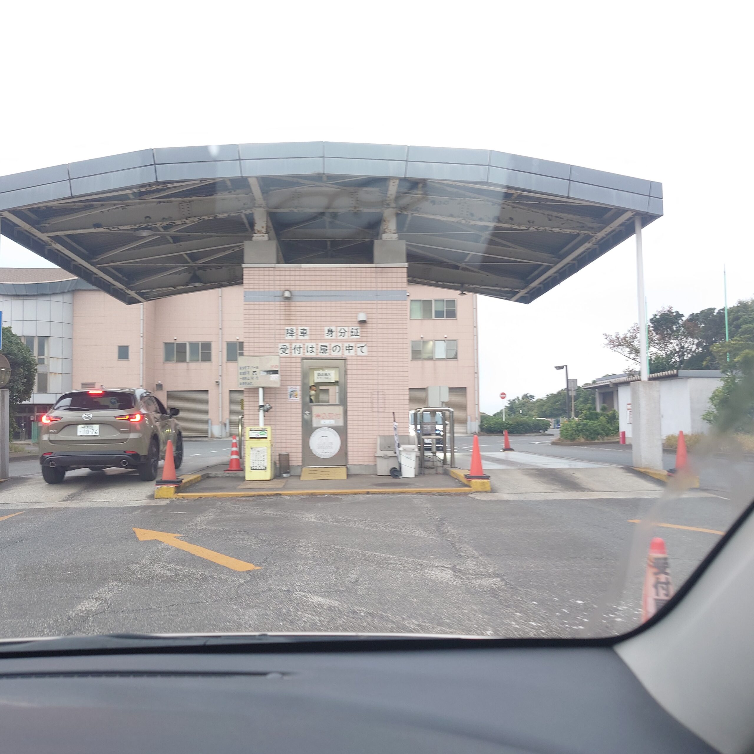 新浜リサイクルセンターの受付棟前で、車列に並びながら搬入手続きを待つ様子。大きな屋根付きのゲートと誘導表示が見える。