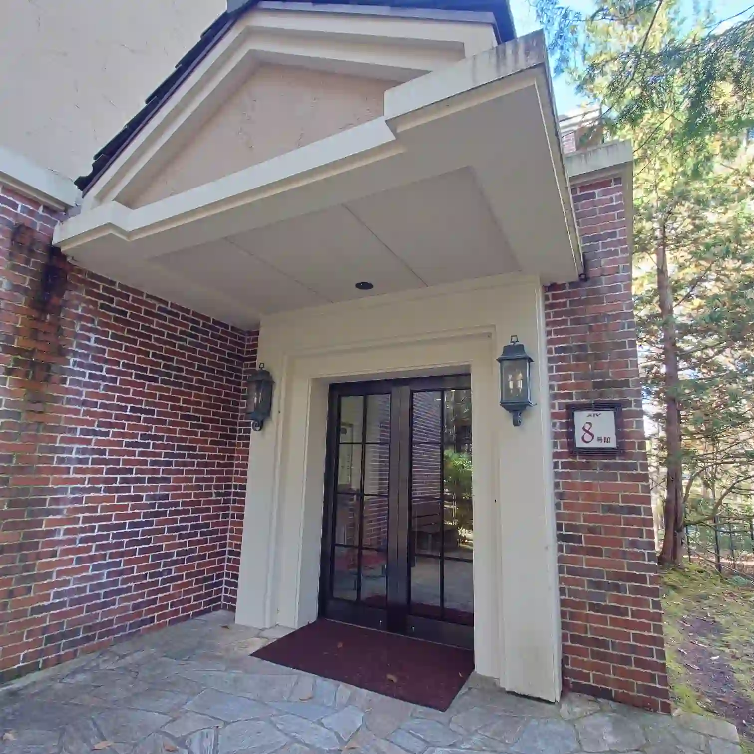 会員制ホテル エクシブ蓼科　スイート棟8号館の入口　レンガ調の外壁とガラス扉　朝の空に青がのぞき女神湖サイクリングへ気持ちが向く