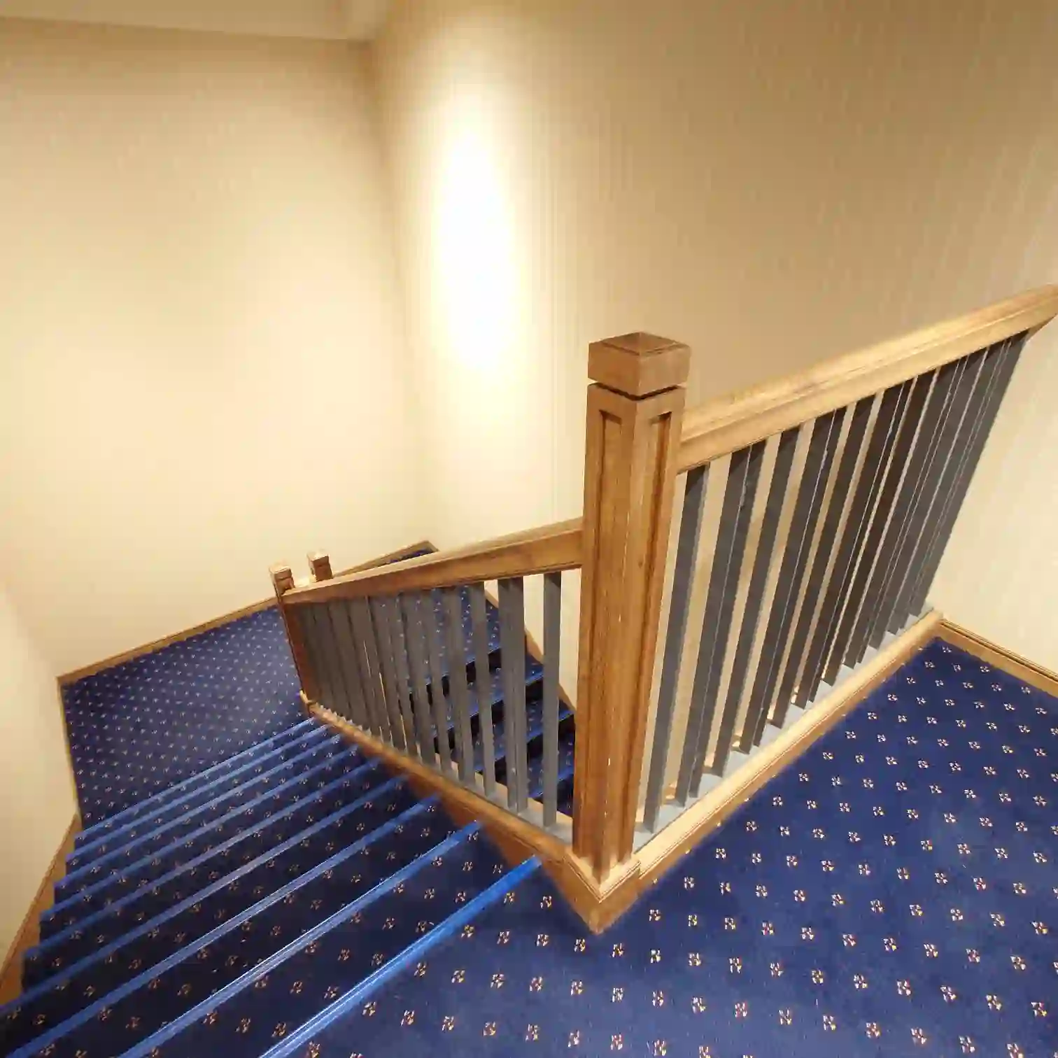 会員制ホテル エクシブ蓼科　裏口へ向かう階段室　青い絨毯と木製手すりが美しい　静かな朝の館内導線