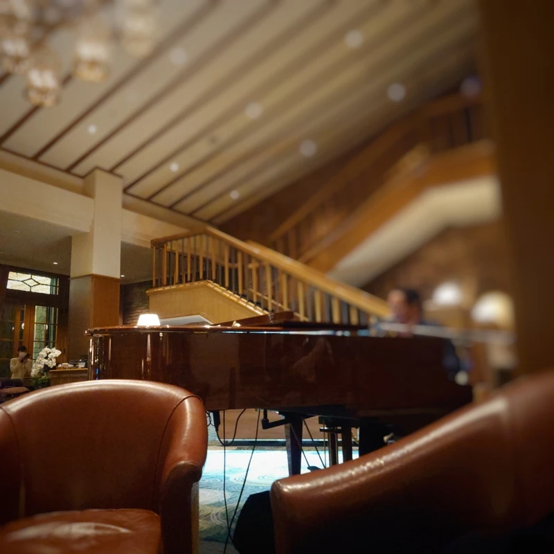 食後にラウンジ「ミルティーユ」でピアノ生演奏を聴く（革張りソファ越しにグランドピアノを眺める）