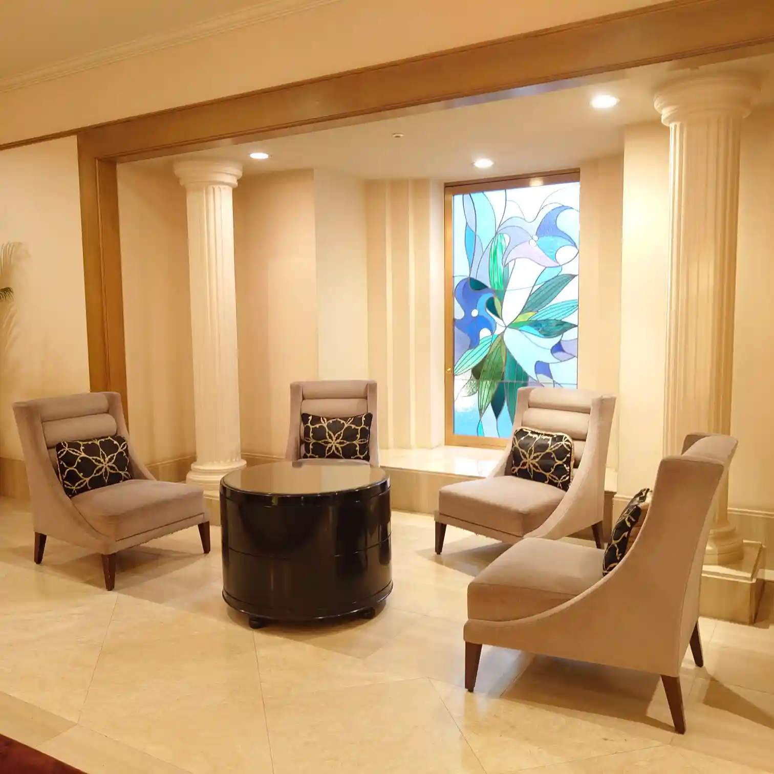 グランドエクシブ軽井沢のラウンジスペース　柱とステンドグラスの前に並ぶ上質なチェア