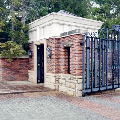 グランドエクシブ軽井沢のエントランスゲート　森の景観に溶け込む重厚な門柱が見えて到着を実感する外観