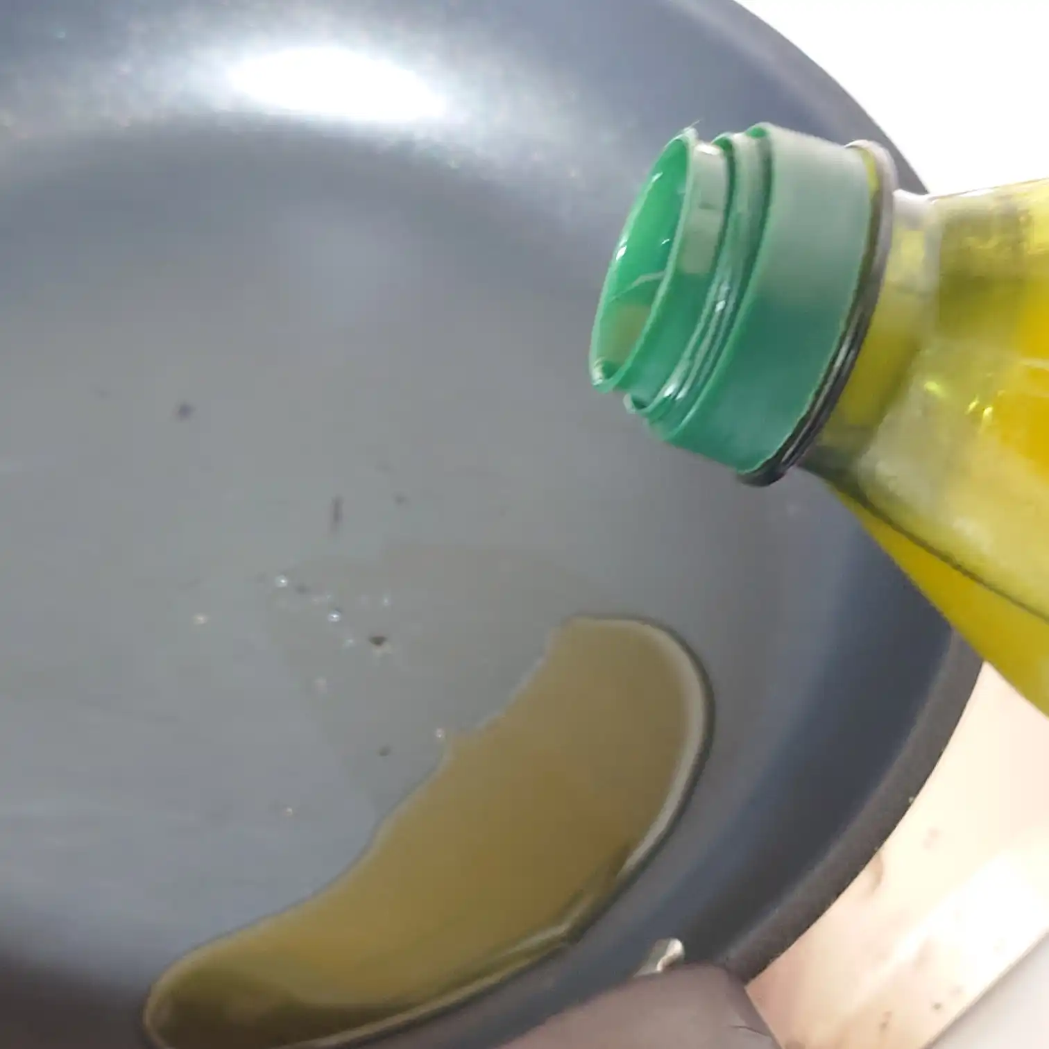 フライパンにオリーブオイルを回し入れる瞬間　リブキャップを焼く前の準備