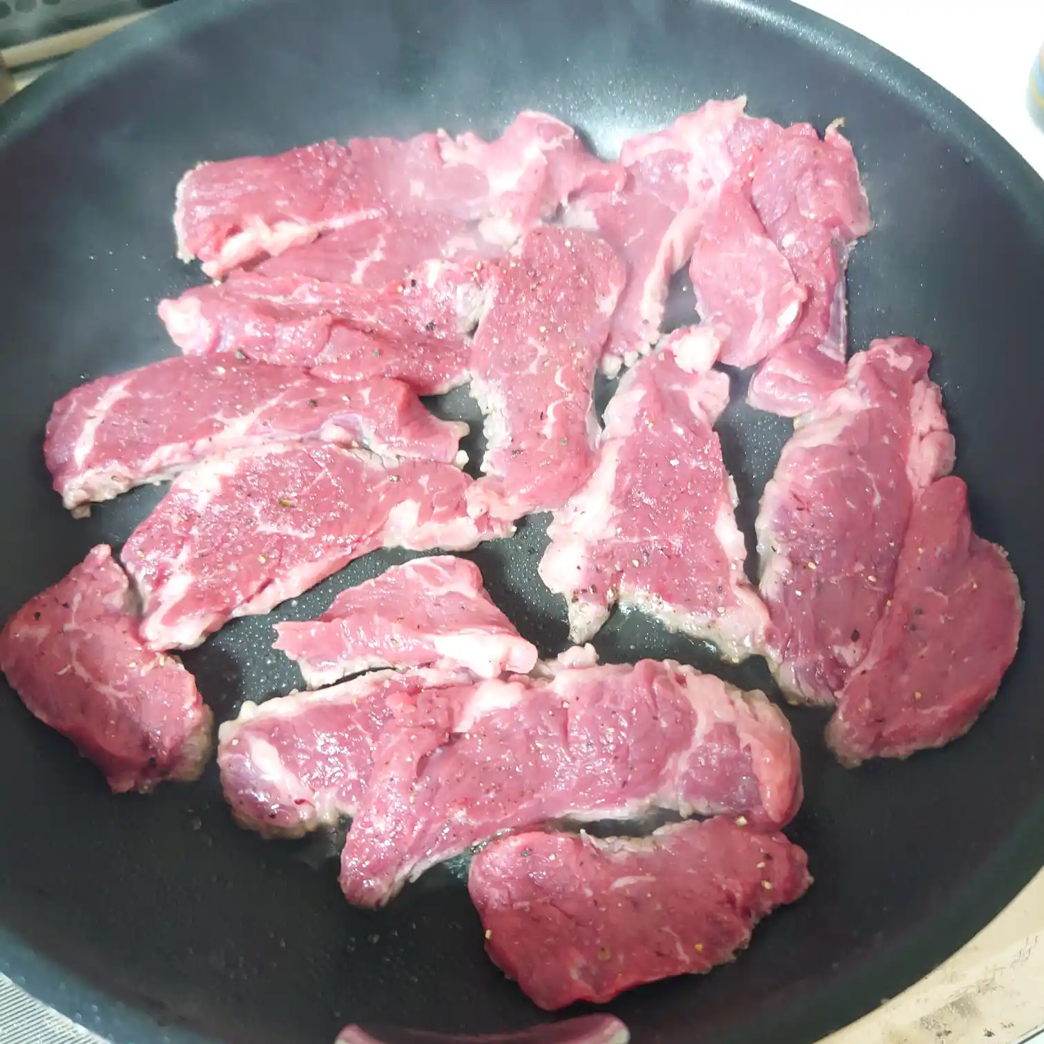 下味を付けたリブキャップのスライスをフライパンに並べた焼き始めの状態　タリアータの火入れ工程