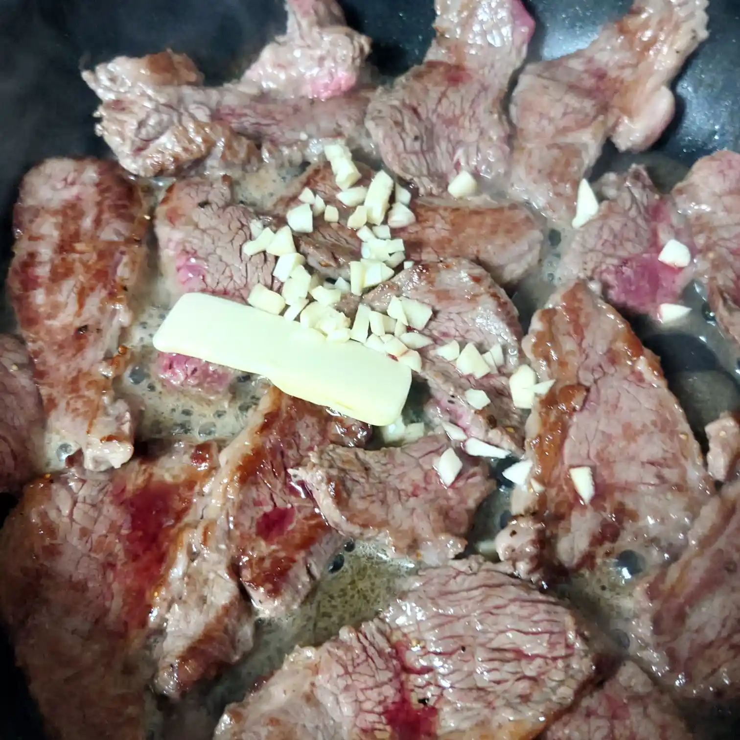 焼いたリブキャップに追いバターと刻みニンニクを入れて香りを立てる工程　ガーリックバターを絡める瞬間