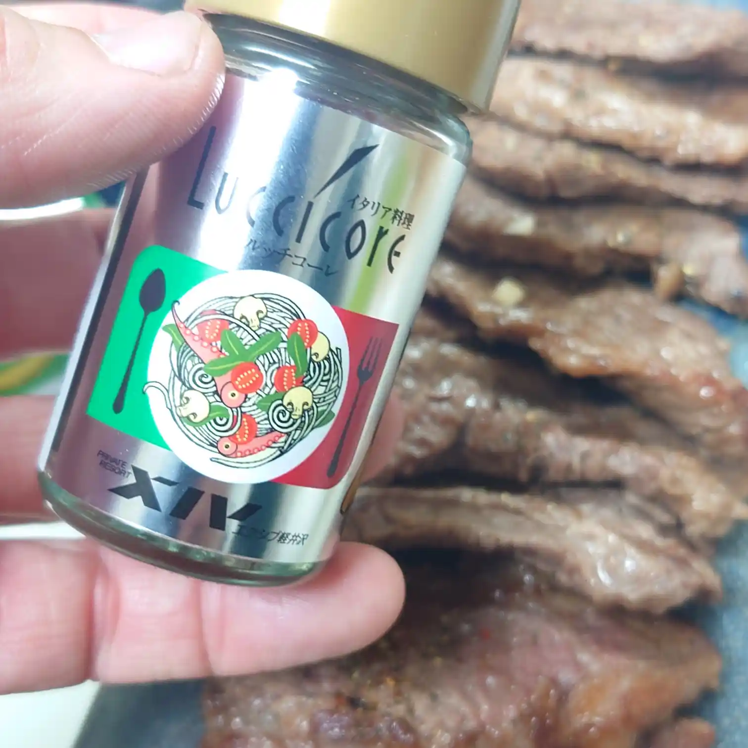 仕上げに使うイタリアン粗挽きペッパー「ルッチコーレ」を持ったカット　焼き上げたリブキャップに追いスパイスする工程